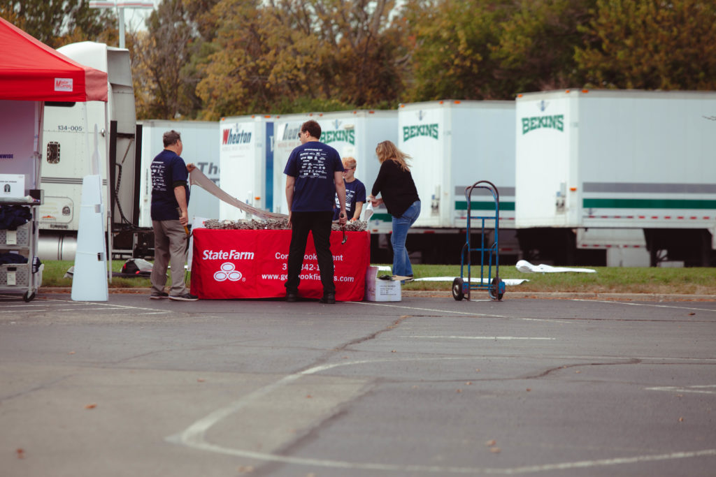 Des bénévoles installent une table de parrainage devant les remorques Bekins lors d'une collecte de fonds pour le camion