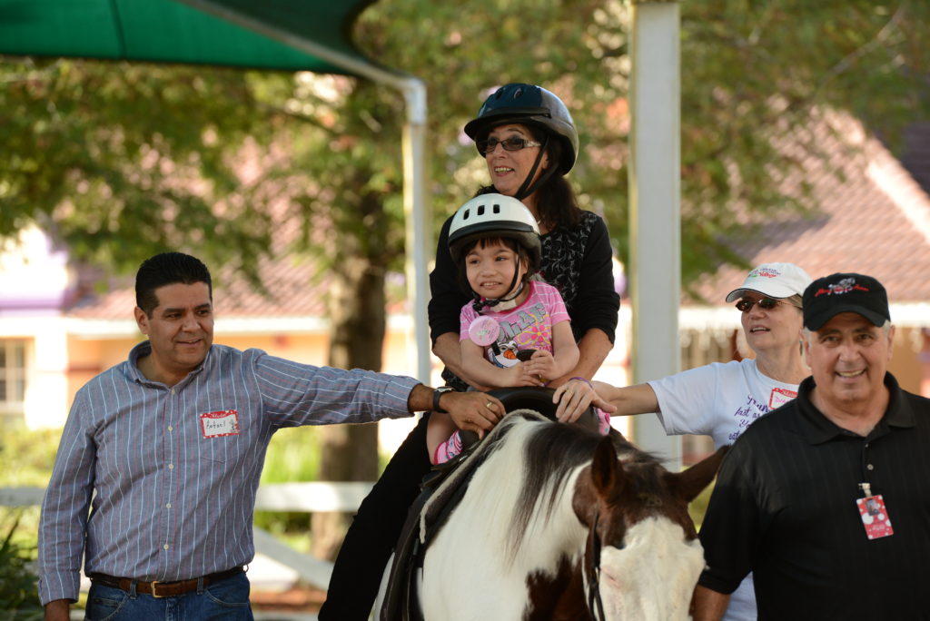 Un enfant avec un casque monte à cheval à Give Kids The World ;  l'argent recueilli lors d'une collecte de fonds en camion soutient l'attraction