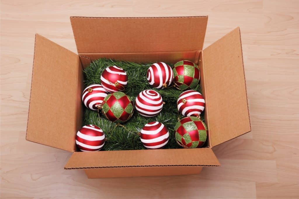 Une boîte pleine de décoration de Noël comprenant des ornements et une guirlande.